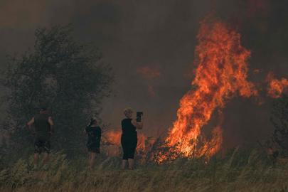 A resident films a wildifre in Tournissan, southwestern France, on August 5, 2025. A fire that broke out on August 5, 2025 afternoon in Ribaute (Aude) had already spread across 1,000 hectares by early evening, according to the prefecture, prompting the evacuation of at least one campsite and several homes, an AFP journalist reported. (Photo by IDRISS BIGOU-GILLES / AFP)