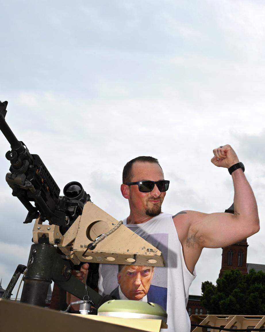 Een man poseert voor een foto met een M240-machinegeweer gemonteerd op een militair voertuig tijdens de grote militaire parade en viering van het Amerikaanse leger.