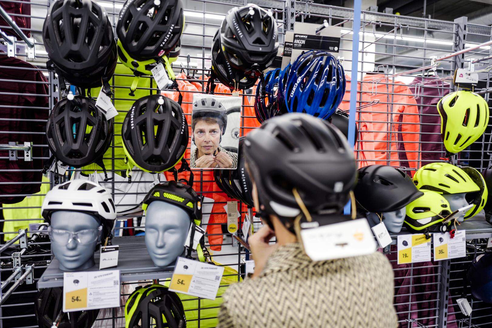 ILLUSTRATIEF 07-10-2023
Vrouw past verschillende fietshelmen voor op haar elektrische fiets in een winkel.