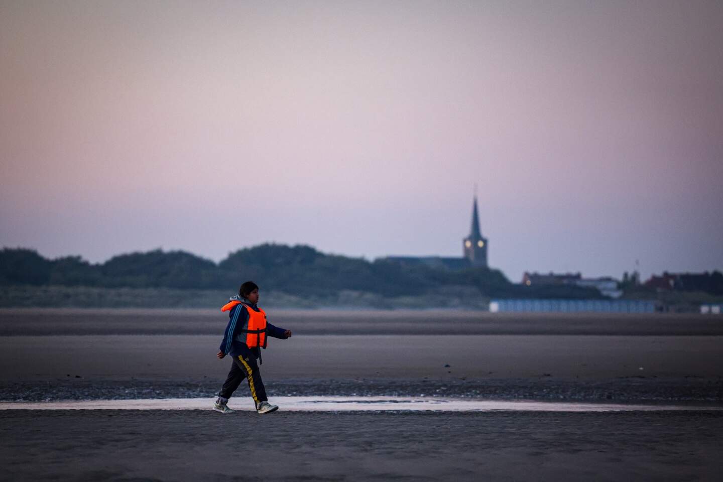 epa12409624 A child wearing a life jacket walks on the beach before boarding an inflatable boat to attempt to cross the English Channel, off the beach of Gravelines, northern France, 27 September 2025.  EPA/FADEL DAWOD