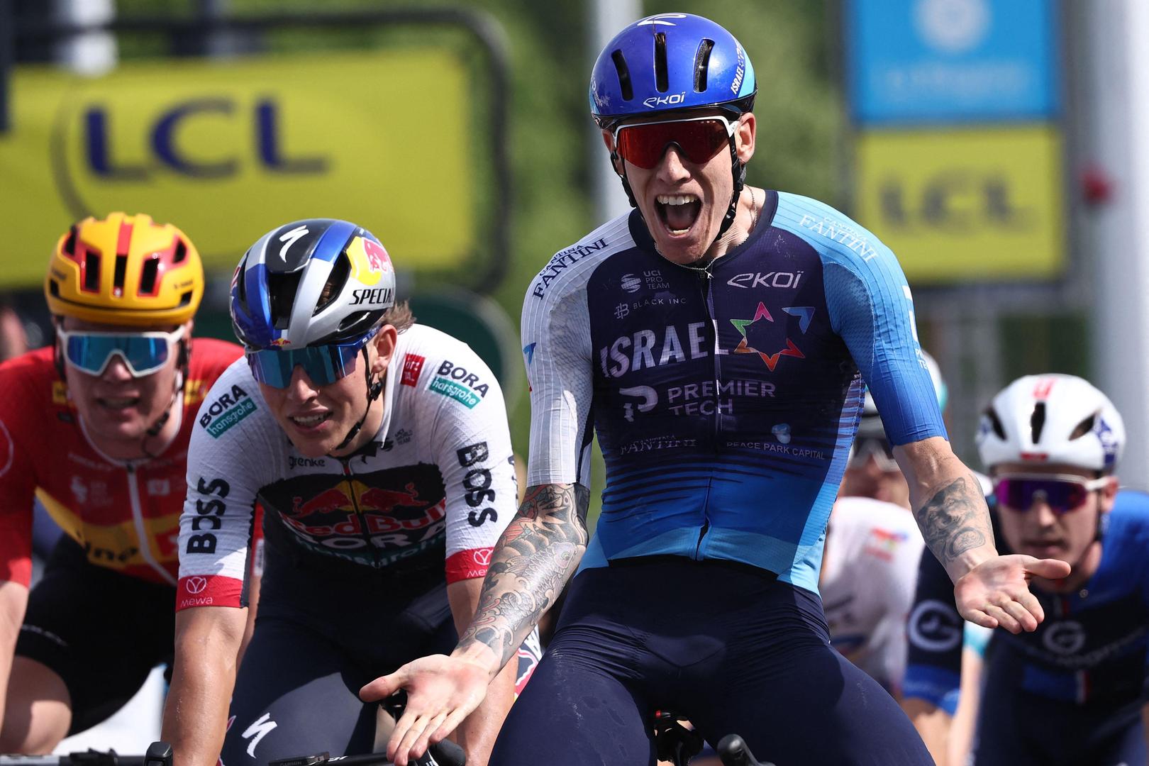 Israel - Premier Tech's British rider Thomas Jake Stewart (centre R) celebrates as he crosses the finish line to win the 5th stage of the 77th edition of the Criterium du Dauphine cycling race, 183 km between Saint-Priest and Mâcon, on June 12, 2025. (Photo by Anne-Christine POUJOULAT / AFP)