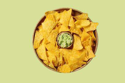 Tortilla nachos corn chips with avocado guacamole sauce served in wood plate over old wooden background. Flat lay. space. (Photo by: Natasha Breen/REDA/Universal Images Group via Getty Images)