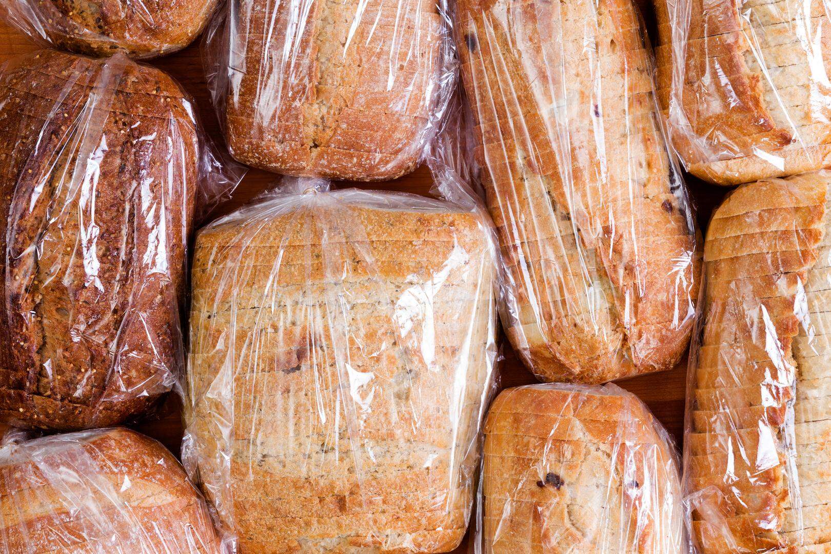 Assortment of different healthy white, wholegrain and wholewheat sliced loaves of fresh bread sealed in plastic bags ready to be distributed in a food drive, full frame overhead view