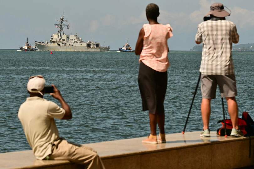 People watch and take pictues of the USS Gravely, a US Navy warship, departing the Port of Port of Spain on October 30, 2025. The US warship arrived in Trinidad and Tobago on October 26, 2025, for joint exercises near the coast of Venezuela, as Washington ratcheted up pressure on drug traffickers and Venezuelan leader Nicolas Maduro. (Photo by MARTIN BERNETTI / AFP)