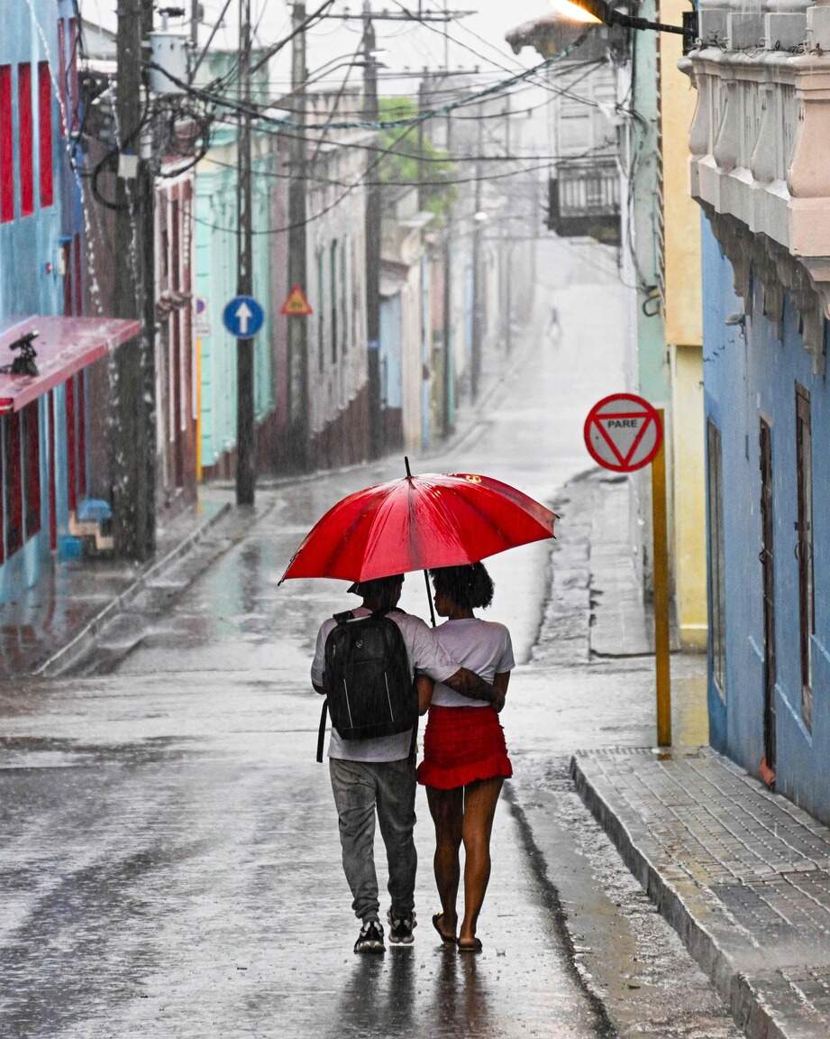 A couple walks in a street before Hurricane Melissa hits the city of Santiago de Cuba, Cuba, on October 28, 2025. (Photo by YAMIL LAGE / AFP)
